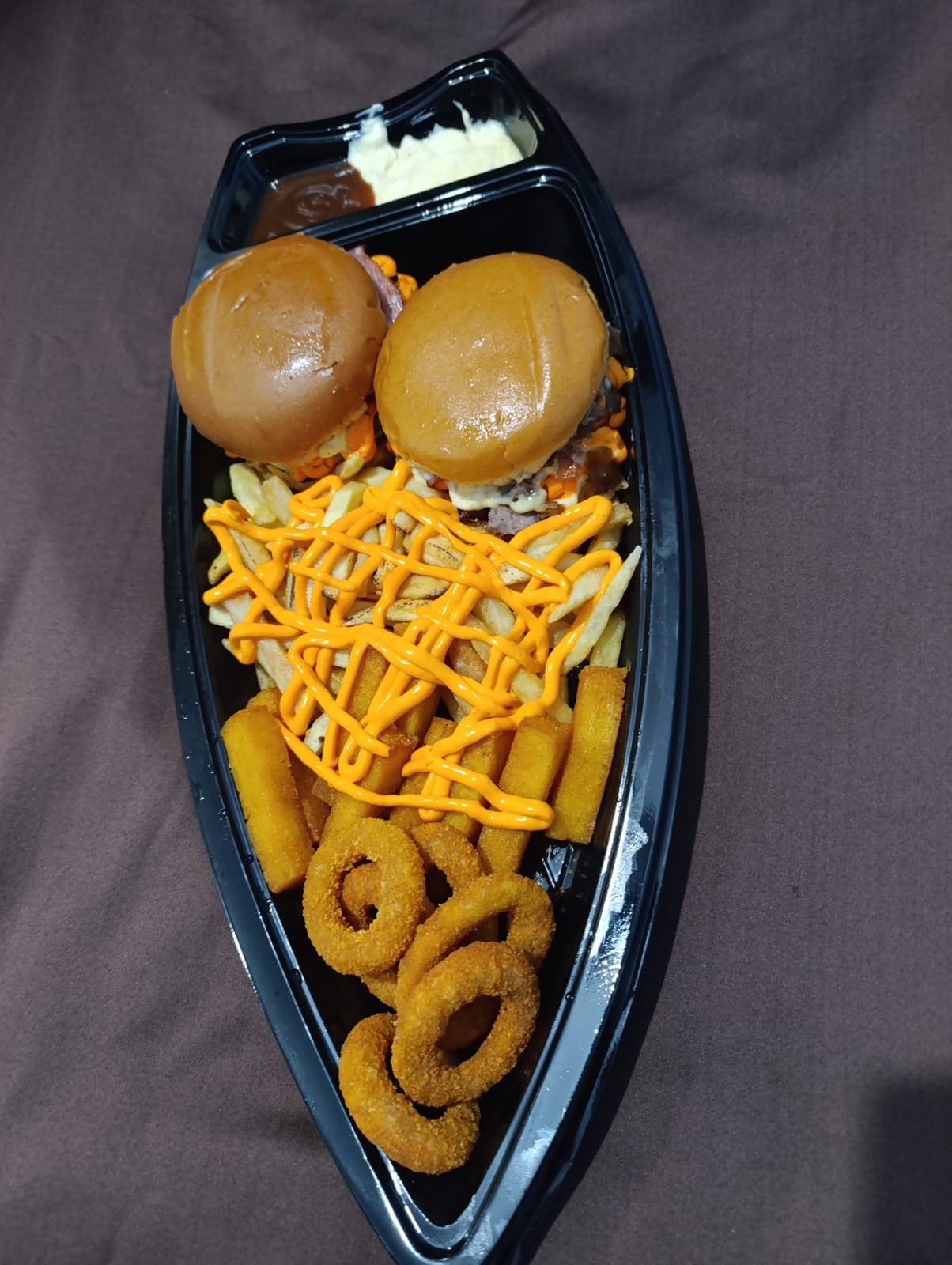 Barca com dois hambúrgueres, batata frita, onion rings e polenta